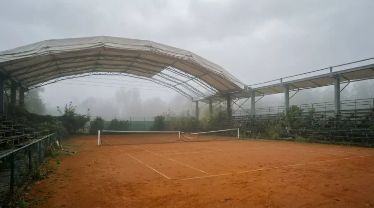 Court en terre battue de Roland Garros sous un ciel nuageux avec le toit rétractable